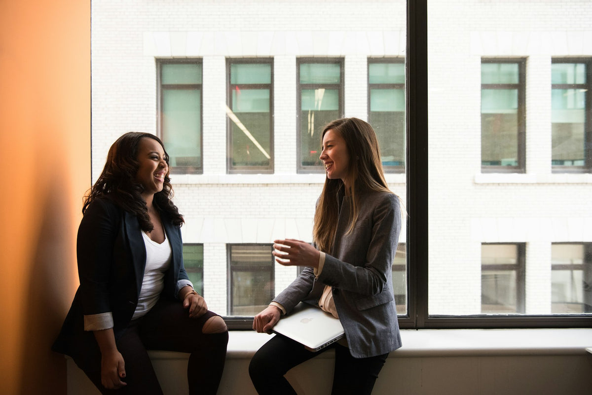 A mentor and mentee talking over coffee in a bright community space